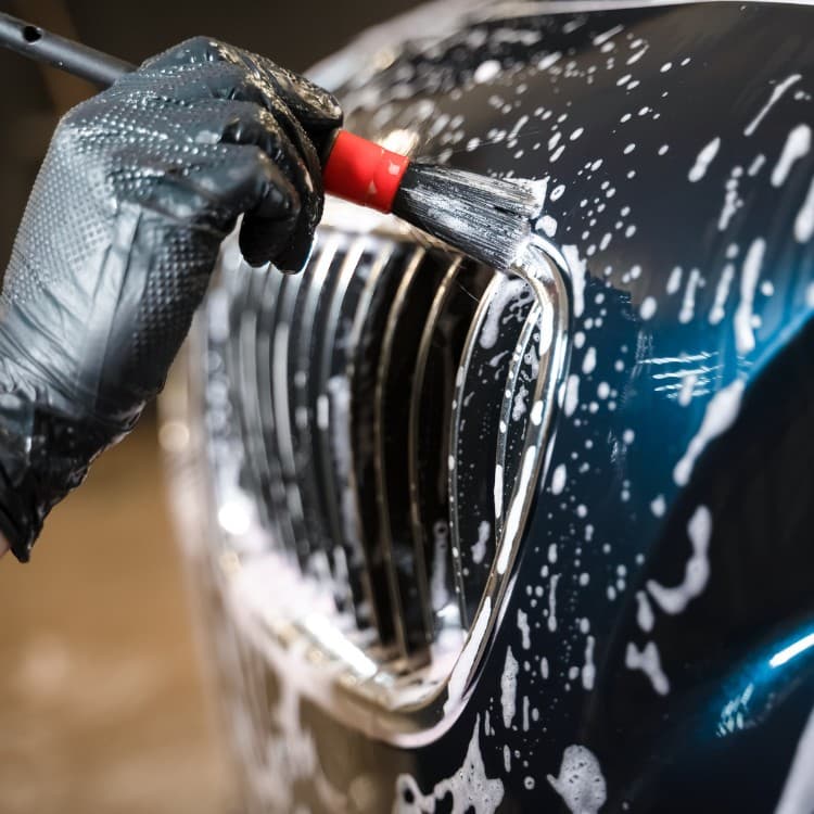 Detailing brush cleaning a soapy front grille