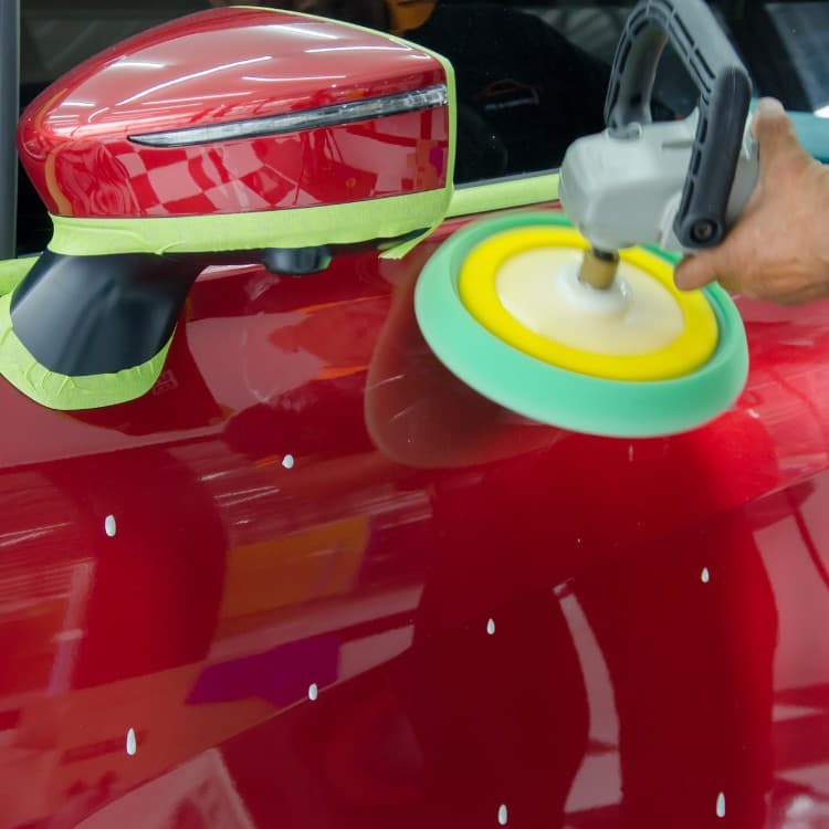 Paint polisher correcting the finish on a red car